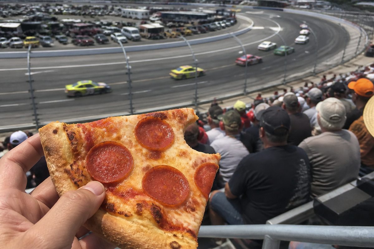 Partially eaten pepperoni pizza slice overlooking the racetrack