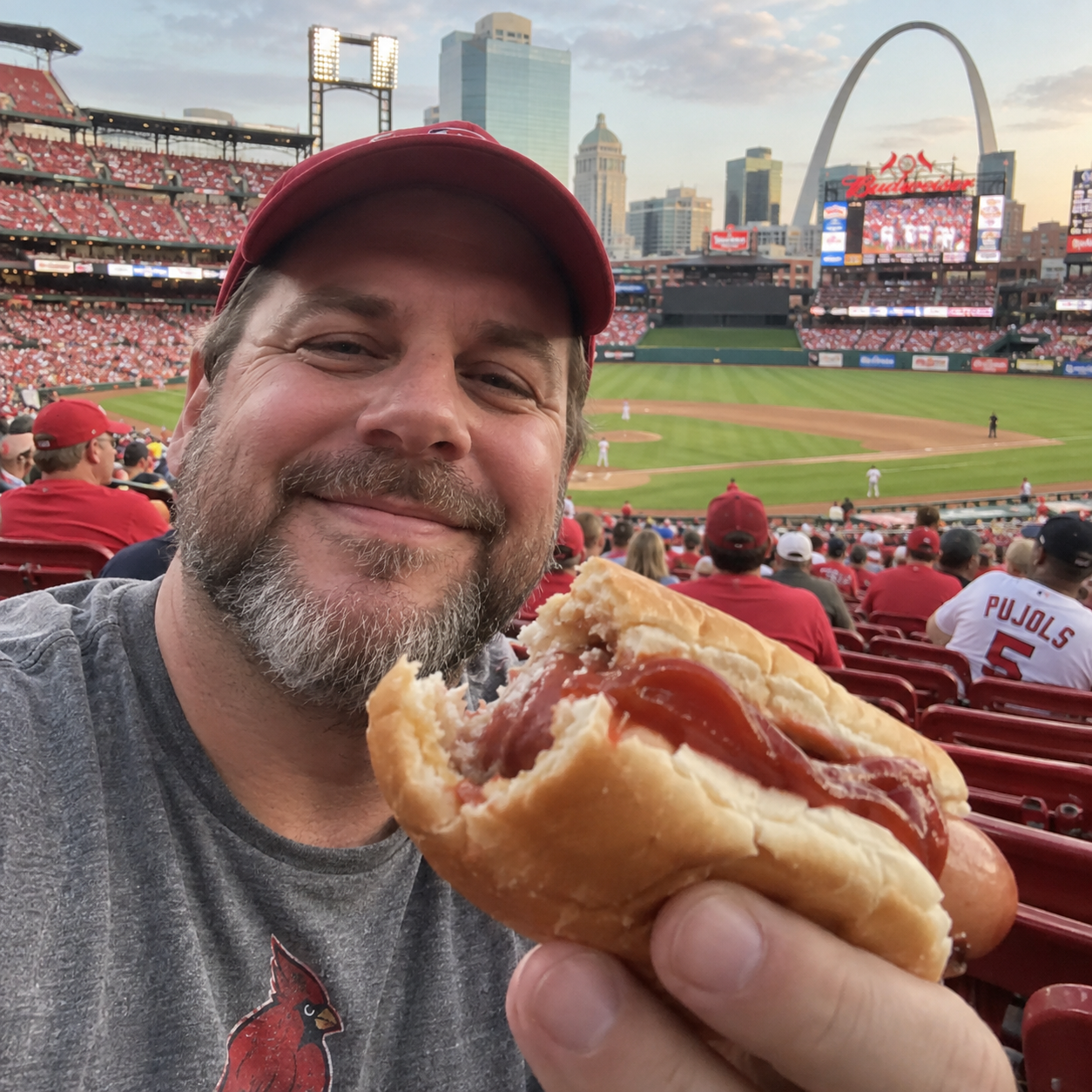 Baseball fan holding a half-eaten ketchup hot dog