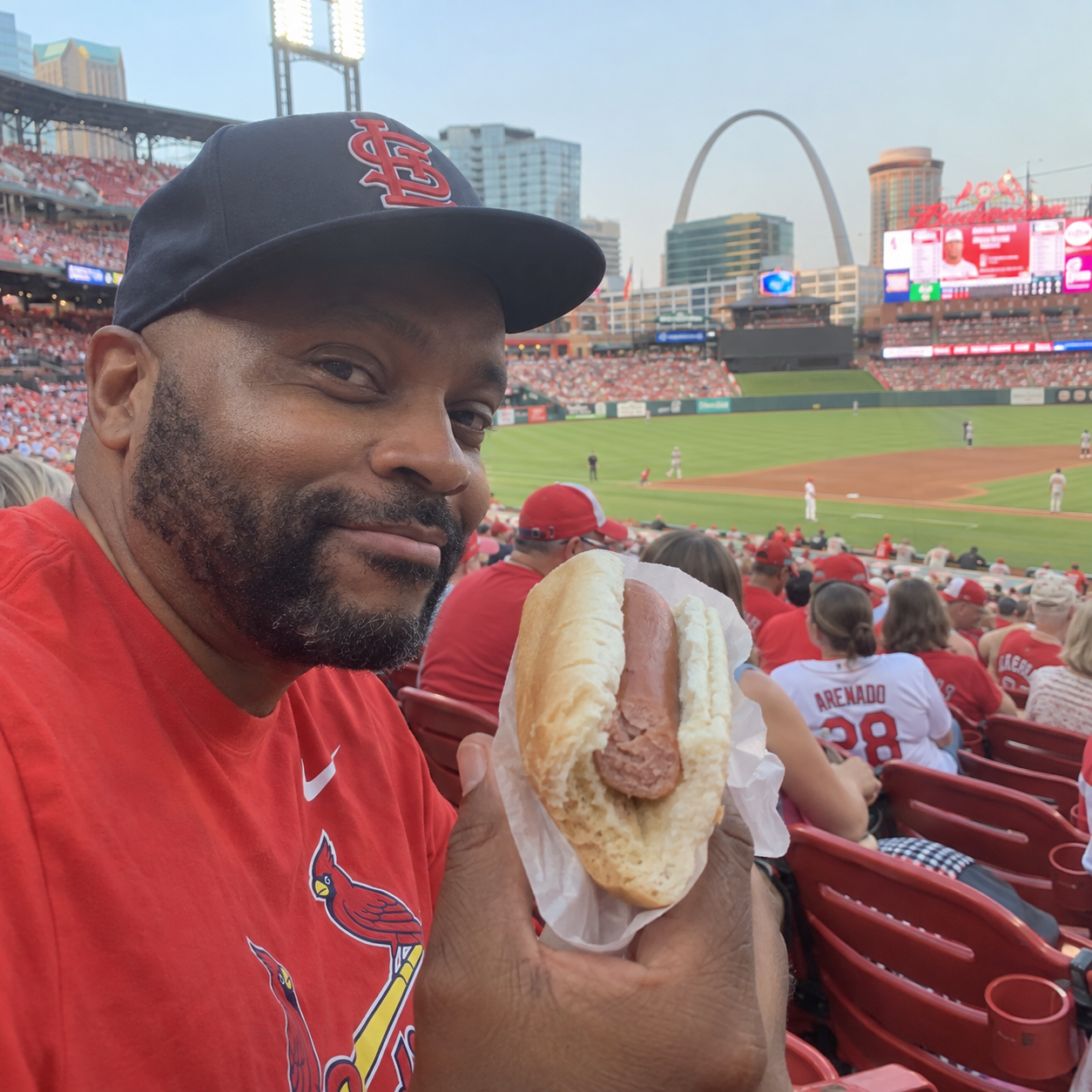 Baseball fan holding a half-eaten plain hot dog in the stands